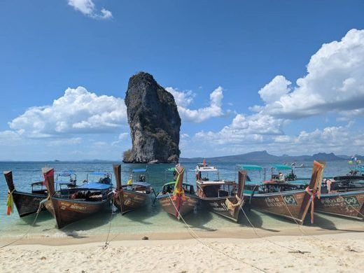 Longtail boats below a rock island