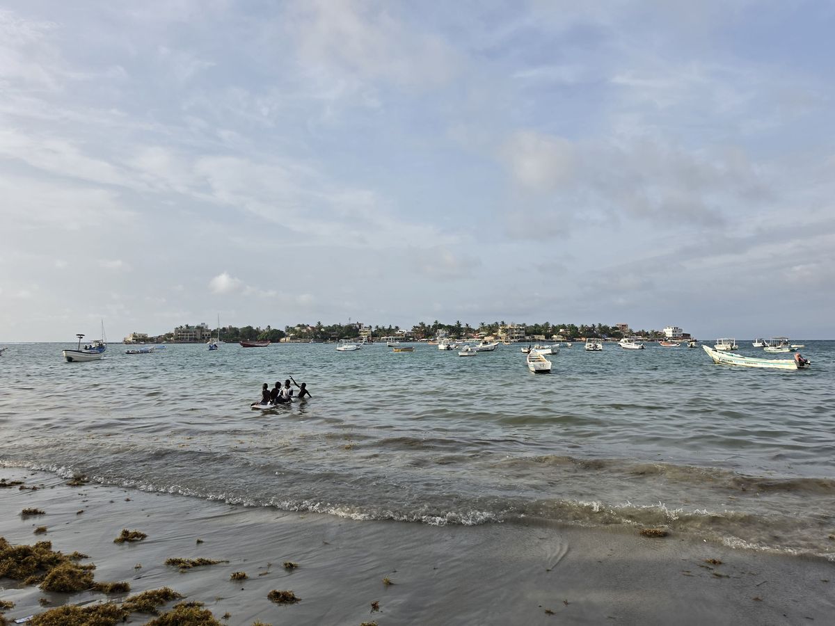 Four kids on a paddleboard, with Ngor Island behind