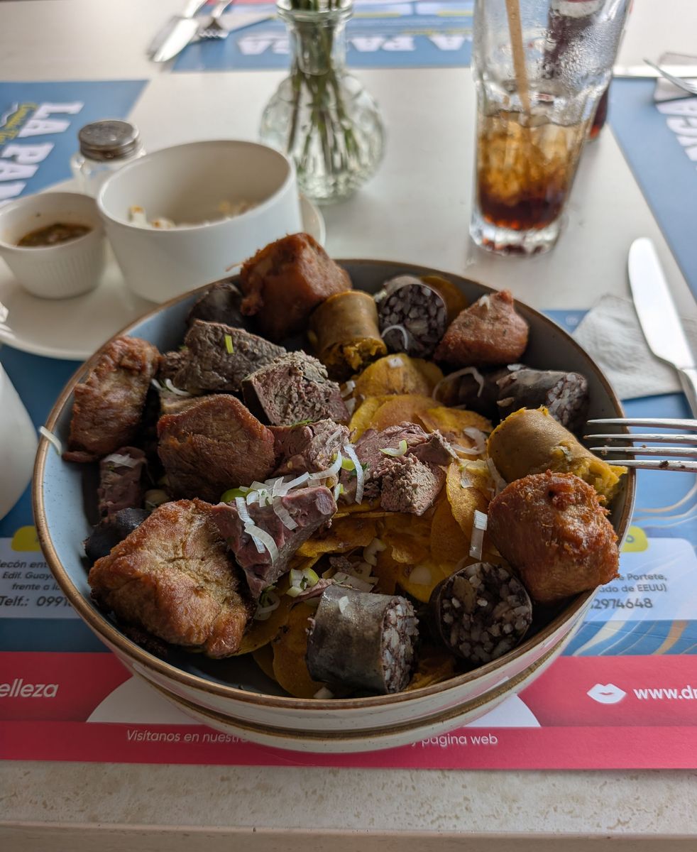 Fried pork, boiled beef, blood sausage and plantain sausage over plantain chips
