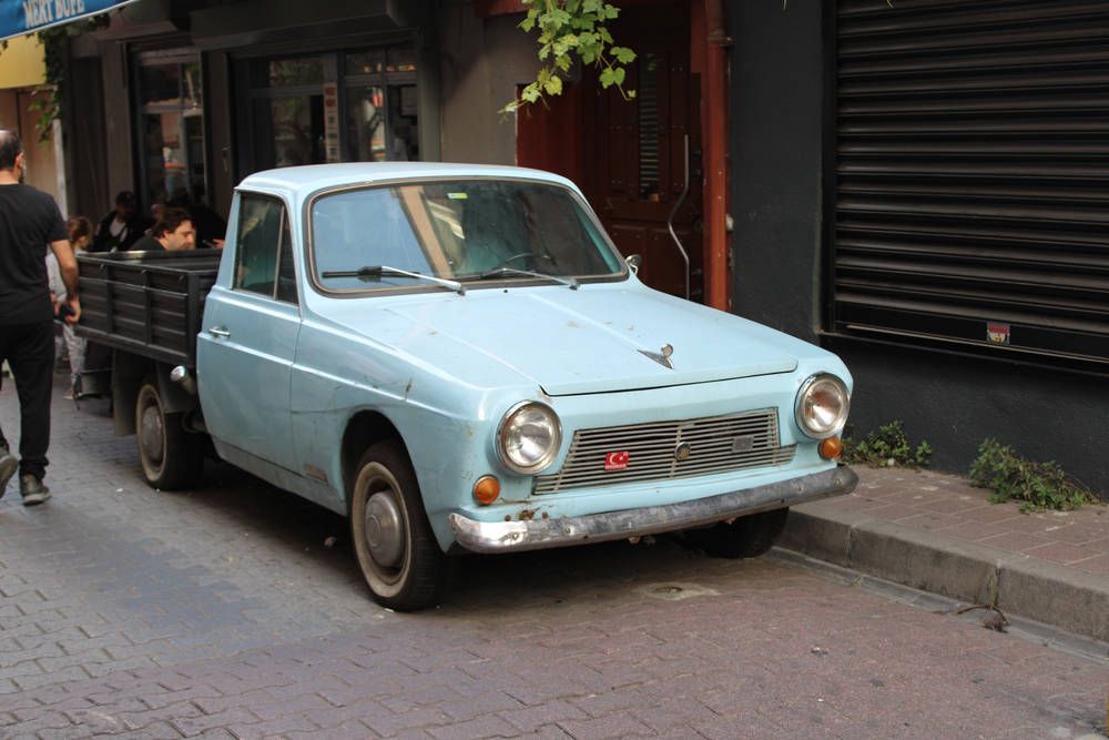 A pale blue old car parked on the street
