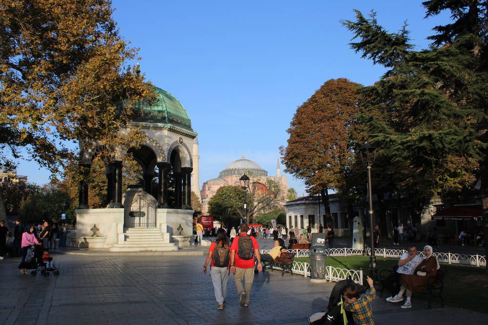 A green-domed fountain with a mosque behind