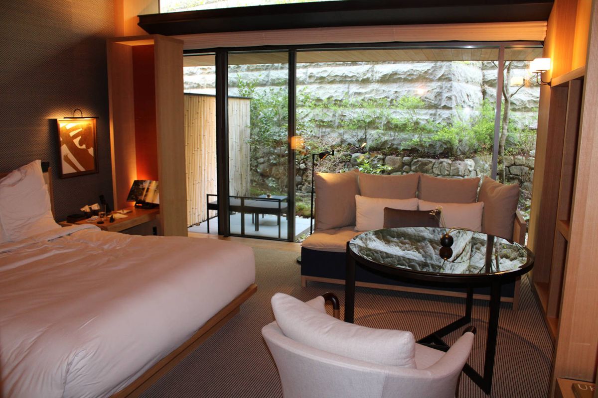 The room: bed, sofa and a round table, a stone wall garden outside
