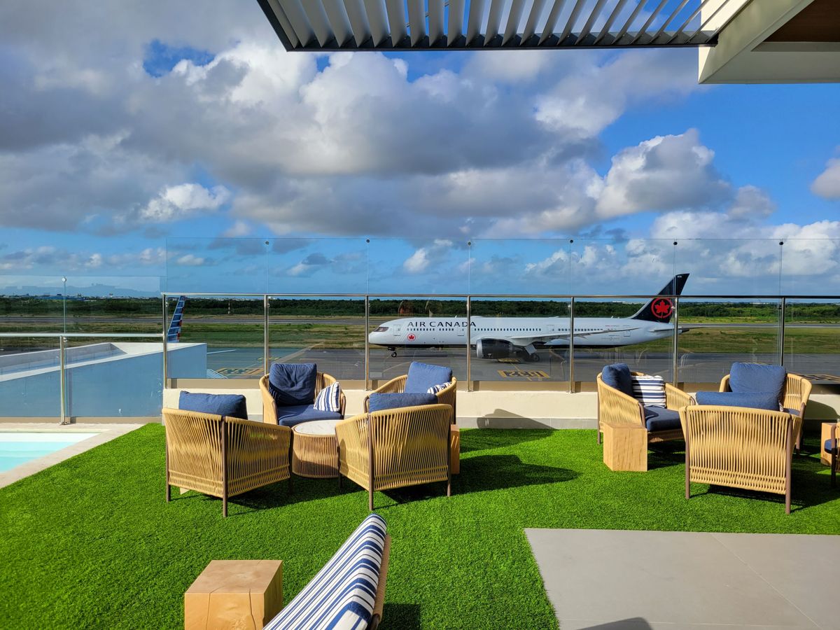 Lounge chairs on the turf, the Air Canada 787 going by