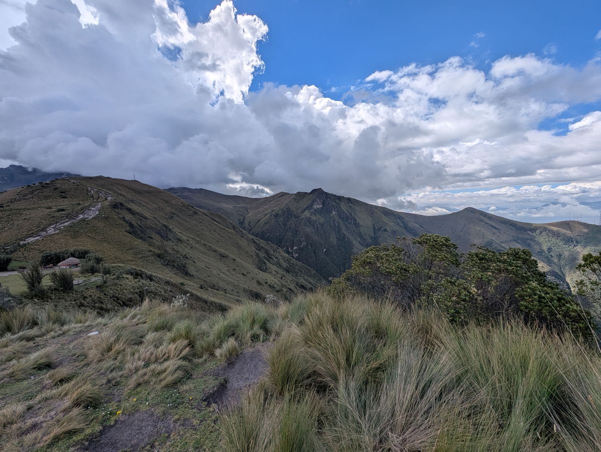 The ridge trail, with a thatched hut below and the peaks behind