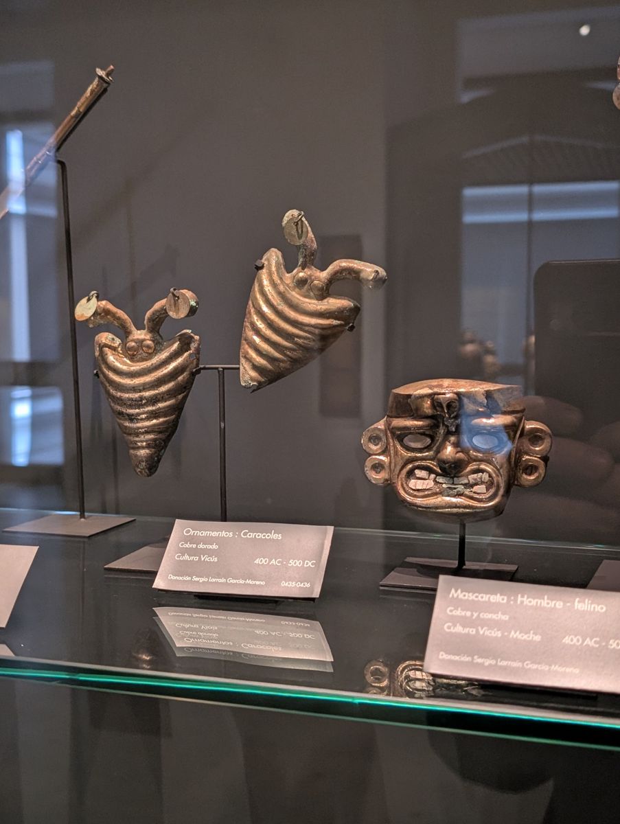 Vicús gilded copper snail ornaments and a mask